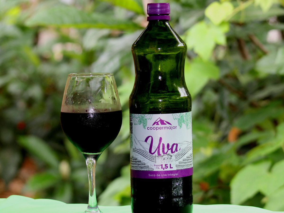Garrafa do suco de uva integral Coopermajor e uma taça servida